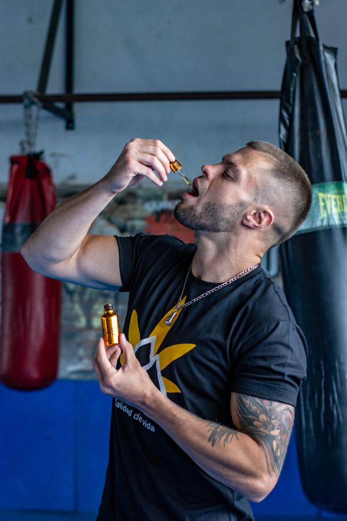 The Art of Drawing Readers In: Your attractive post title goes here Athletic man in gym holds CBD oil, emphasizing fitness and wellness.